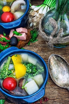 traditional soup of fresh vegetables in blue pot on wooden background.Photo tinted