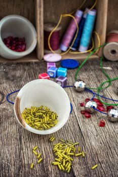 vases with small beads on the background of tools for needlework.Selective focus.Photo tinted