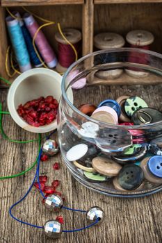 vase with buttons and different tools for needlework beading and sewing .Selective focus