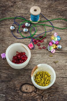 set of beads in stacks on wooden table with tools for needlework.Selective focus.Photo tinted