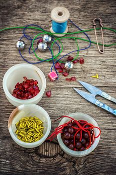 set of beads in stacks on wooden table with tools for needlework.Selective focus.Photo tinted