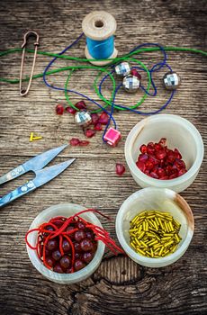 set of beads in stacks on wooden table with tools for needlework.Selective focus.Photo tinted