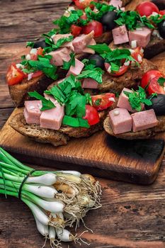 sandwiches with meat ,fresh tomatoes, onions and olives on wooden table top.Photo tinted
