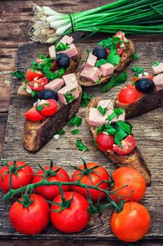sandwiches with meat ,fresh tomatoes, onions and olives on wooden table top.Photo tinted