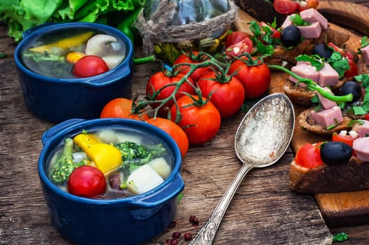 traditional soup of fresh vegetables in blue pot on wooden background.Photo tinted