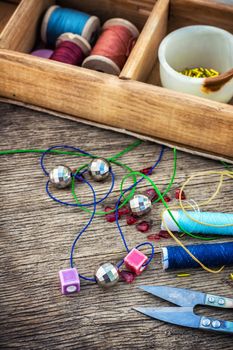 set of beads in stacks on wooden table with tools for needlework.Selective focus.Photo tinted