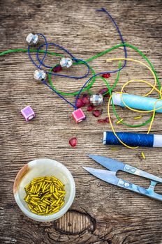 set of beads in stacks on wooden table with tools for needlework.Selective focus.Photo tinted