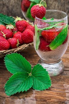 glass with drink of strawberries and mint on the background of the basket full berries.Selective focus.Photo tinted
