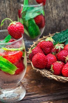 glass with drink of strawberries and mint on the background of the basket full berries.Selective focus.Photo tinted