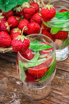 glass with drink of strawberries and mint on the background of the basket full berries.Selective focus.Photo tinted