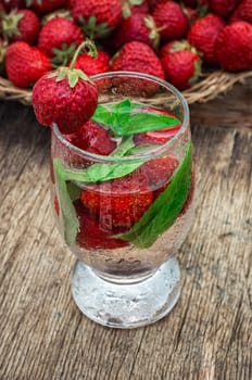 glass with drink of strawberries and mint on the background of the basket full berries.Selective focus.Photo tinted