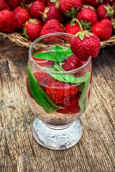 glass with drink of strawberries and mint on the background of the basket full berries.Selective focus.Photo tinted