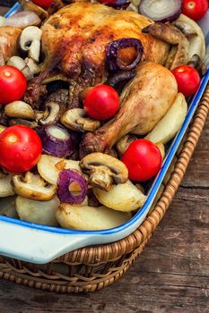 young chicken baked with potatoes,mushrooms and vegetables in the baking dish.