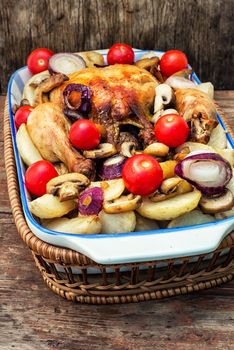 young chicken baked with potatoes,mushrooms and vegetables in the baking dish.Photo tinted.Selective focus