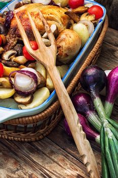 young chicken baked with potatoes,mushrooms and vegetables in the baking dish.