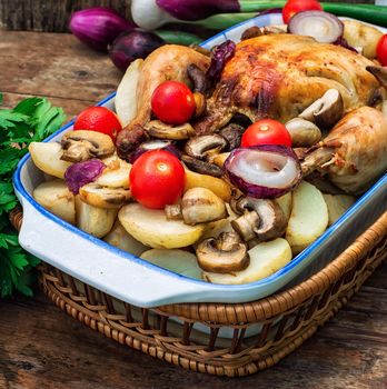 young chicken baked with potatoes,mushrooms and vegetables in the baking dish.Photo tinted.Selective focus