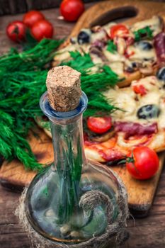 delicious meat pizza with bacon and olives on bottles of olive oil.The image is tinted