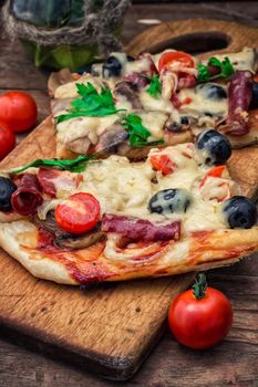 meat pizza made with salami,cheese,mushrooms,cherry tomatoes and olives.The image is tinted.Selective focus