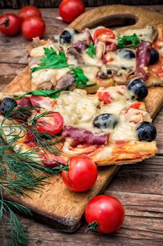 meat pizza made with salami,cheese,mushrooms,cherry tomatoes and olives.The image is tinted.