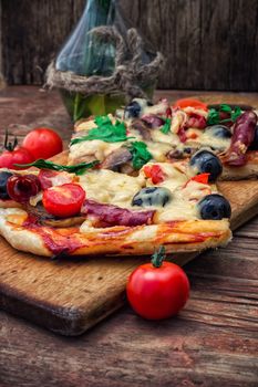 meat pizza made with salami,cheese,mushrooms,cherry tomatoes and olives.The image is tinted.