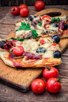 meat pizza made with salami,cheese,mushrooms,cherry tomatoes and olives.The image is tinted.