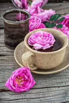 Cup with fresh fragrant herbal decoction of tea rose.The image is tinted