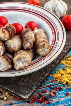 Turkey sausages roasted on round plate on wooden surface with tomatoes and spices.