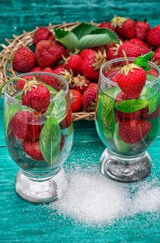 glass with drink of strawberries and mint on the background of the basket full berries.Selective focus.Photo tinted