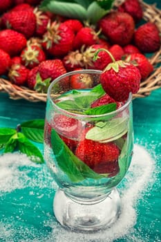 glass with drink of strawberries and mint on the background of the basket full berries.Selective focus.Photo tinted