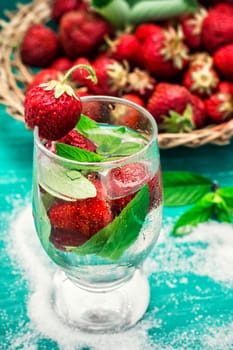 glass with drink of strawberries and mint on the background of the basket full berries.Selective focus.Photo tinted