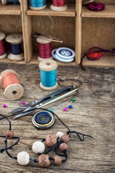 beads,thread,buttons craftswomen on wooden background.Selective focus.Photo tinted