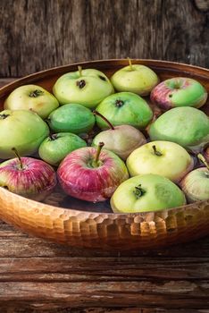Autumn harvest of apples in the bowl of water on wooden background.Photo tinted.