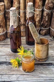 infusion of inflorescences and roots of the medicinal plant Inula on the wooden table next mortar and pestle.Photo tinted.