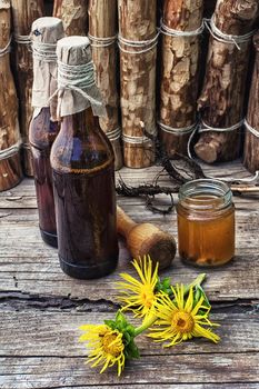 infusion of inflorescences and roots of the medicinal plant Inula on the wooden table next mortar and pestle.Photo tinted.