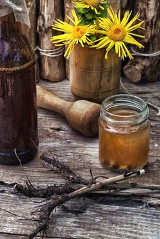 infusion of inflorescences and roots of the medicinal plant Inula on the wooden table next mortar and pestle.Photo tinted.