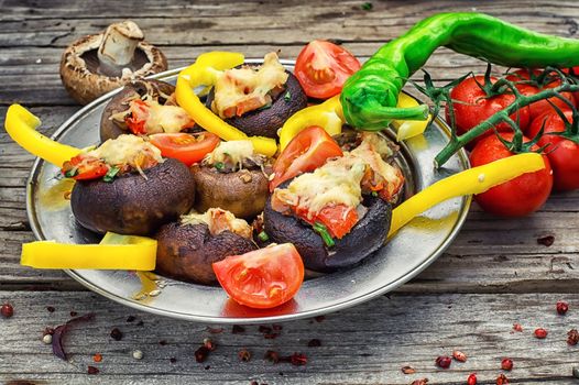 Easy appetizer of mushrooms stuffed with cheese,garlic and tomatoes.Rustic kitchen.Photo tinted.