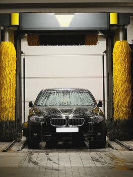 Black car washing in station washing tunnel