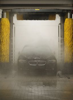 Black car in fog washing in station washing tunnel