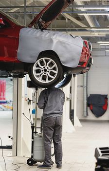 mechanic repairing suspension in car in big and clean garage