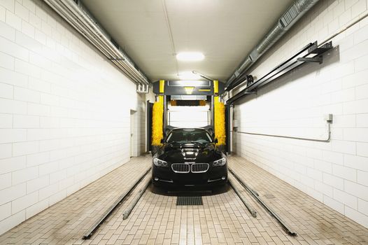 Black clean car in white station washing tunnel