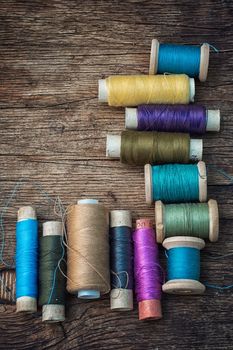 spools of thread on the old wooden background.Photo tinted