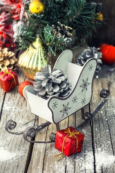 Christmas sleigh with pine cones and decorations on wooden background.