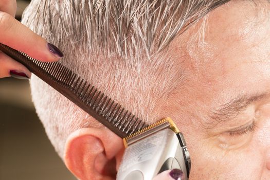 woman cuts hair with scissors, razor in  professional hairdressing salon