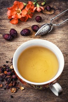 Cup of flower tea, on wooden table in vintage style.Photo tinted.