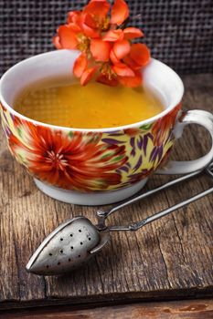 Cup of flower tea, on wooden table in vintage style.Photo tinted.