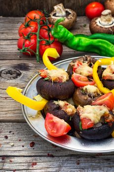 Easy appetizer of mushrooms stuffed with cheese,garlic and tomatoes.Rustic kitchen.Photo tinted.Selective focus