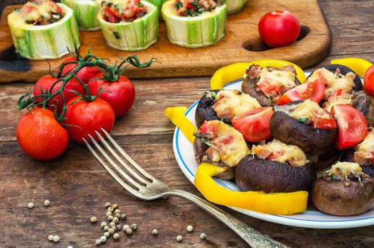 Easy appetizer of mushrooms stuffed with cheese,garlic and tomatoes.Rustic kitchen.Photo tinted.Selective focus