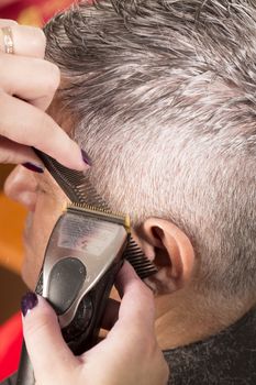 woman cuts hair with scissors, razor in  professional hairdressing salon