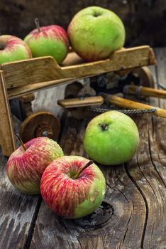 The crop of apples on wooden background on the background of the symbolic scale model of farmer's wagon.Photo tinted