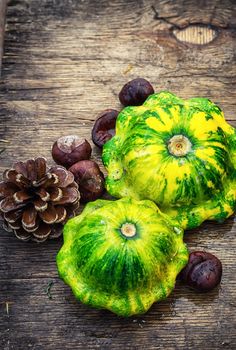 Autumn harvest squash with chestnuts and pine cones on wooden table